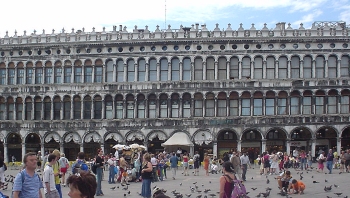 the Venetian gothic facade of St. Marks basilica can be seen. The Venetian Gothic style shows the characteristic eastern influence that was favored in the 11th century.